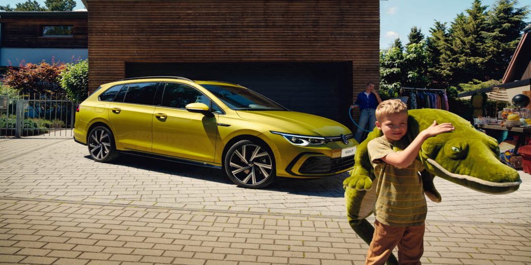 Yellow VW Golf Variant side view with kid and its crocodile plush toy