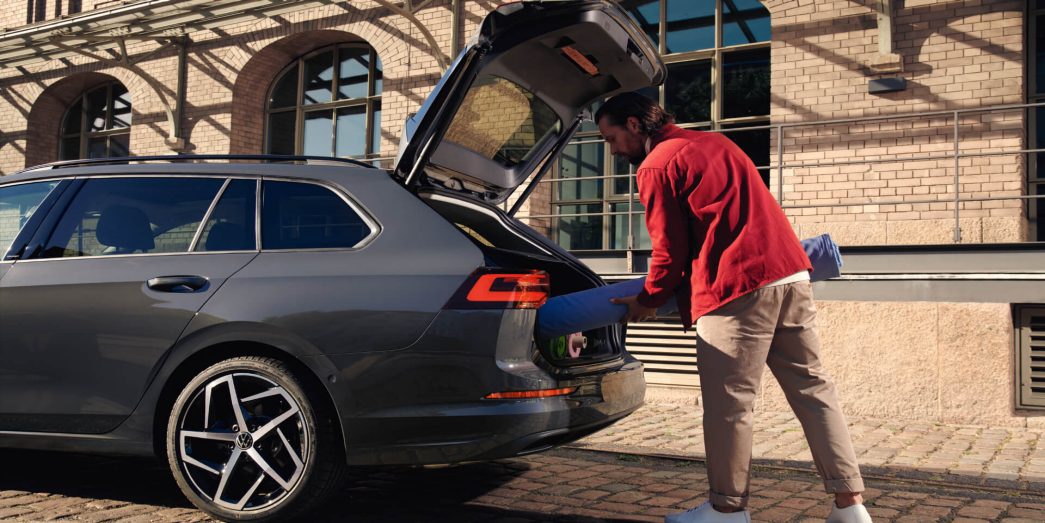 Back of the VW Golf Variant with open trunk and a man