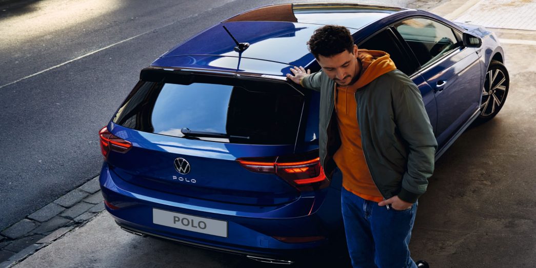 Blue VW Polo rear view with man next to it