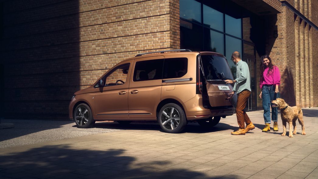 VW Caddy vue latérale avec un couple et un chien