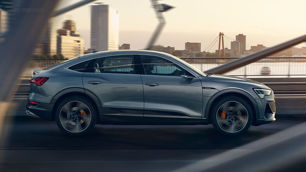 Grey Audi e-tron side view driving over a bridge