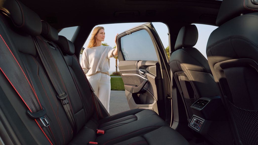 Back seats of the Audi Q8 e-tron with woman standing next to an open door