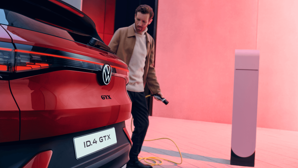 VW ID.4 GTX rouge vue arrière avec homme et station de recharge