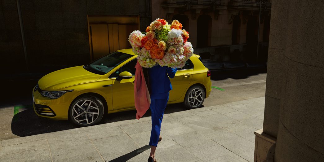 VW Golf jaune avec personne et des fleurs