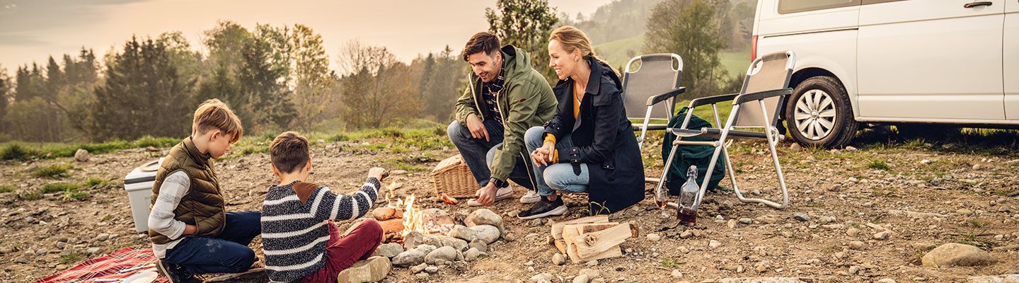 Family with camper in nature around campfire