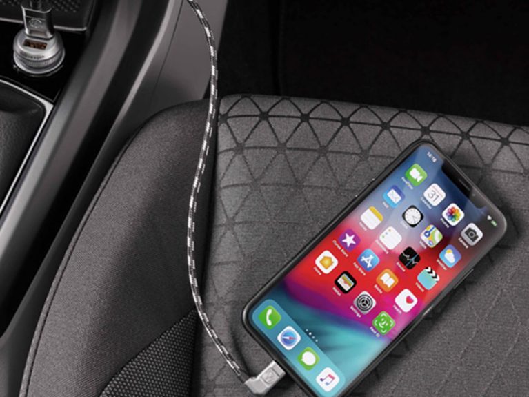 Smartphone mit Ladekabel auf dem Beifahrersitz